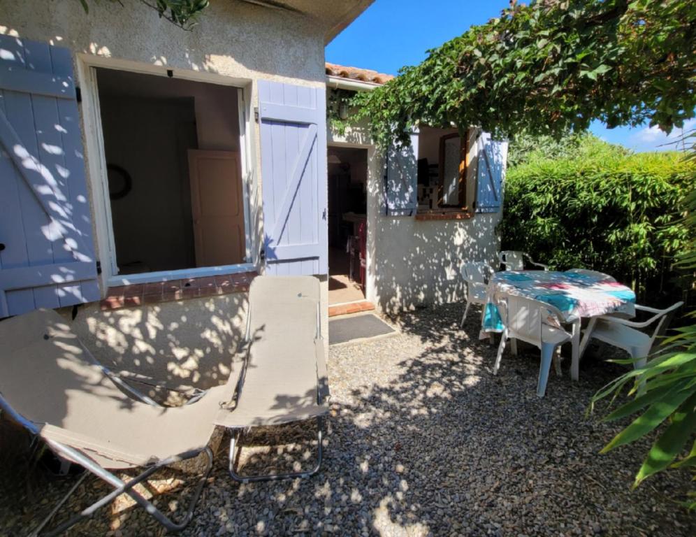 une table et des chaises assises à l'extérieur d'une maison dans l'établissement Cottage 43 m2 2 épis - Plage à 400m - PARKING Jardin TERRASSE Wifi, à Six-Fours-les-Plages