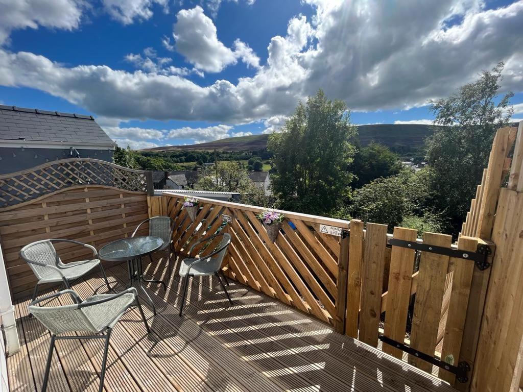 a wooden deck with two chairs and a table on it at Cosy cottage with beautiful mountain views in Blaenavon