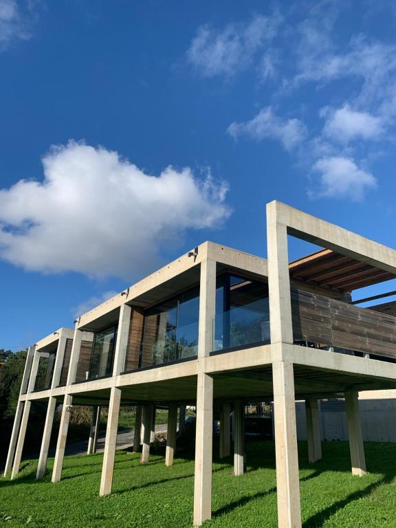 a large building with pillars in the grass at Glass Cube in Outes