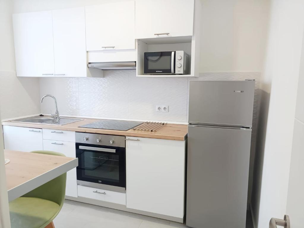 Biała kuchnia z lodówką i kuchenką mikrofalową w obiekcie A Capelada-Céntrico apartamento en Cedeira w mieście Cedeira