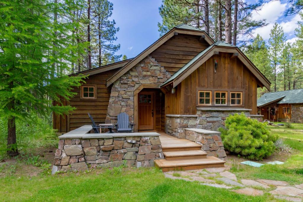 a log cabin with a porch and stairs to the door at Lake Creek Lodge in Camp Sherman