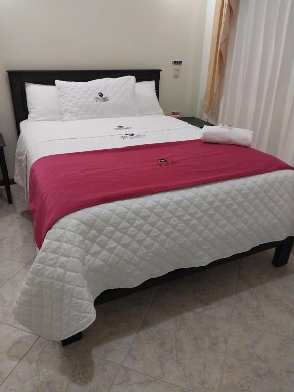 Una gran cama blanca con una manta roja. en Hotel Oro Negro, en Puyo
