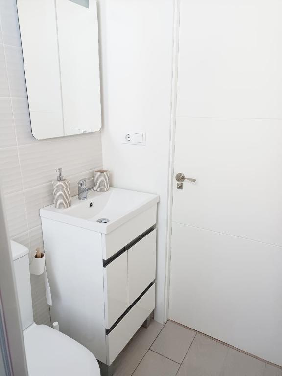 biała łazienka z umywalką i lustrem w obiekcie A Capelada-Céntrico apartamento en Cedeira w mieście Cedeira
