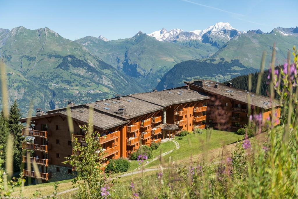 a hotel on a hill with mountains in the background at Résidence Pierre & Vacances Premium Le Roselend in Arc 1800