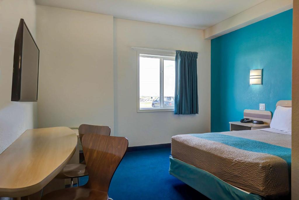 a hotel room with a bed and a table and a window at Motel 6-Grande Prairie, AB in Grande Prairie