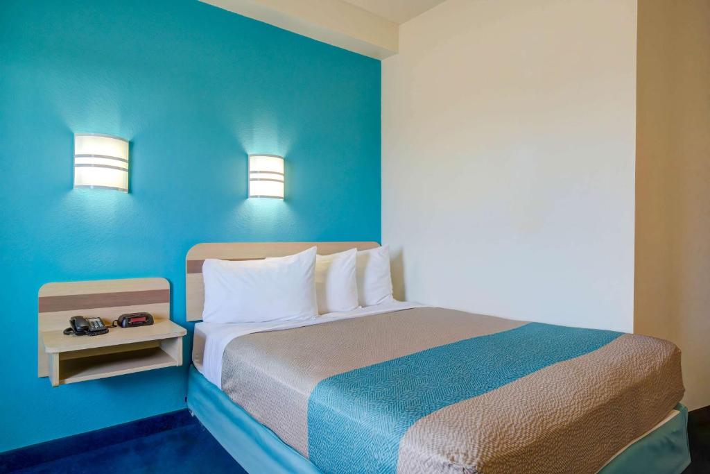 a bedroom with a bed with a blue wall at Motel 6-Grande Prairie, AB in Grande Prairie