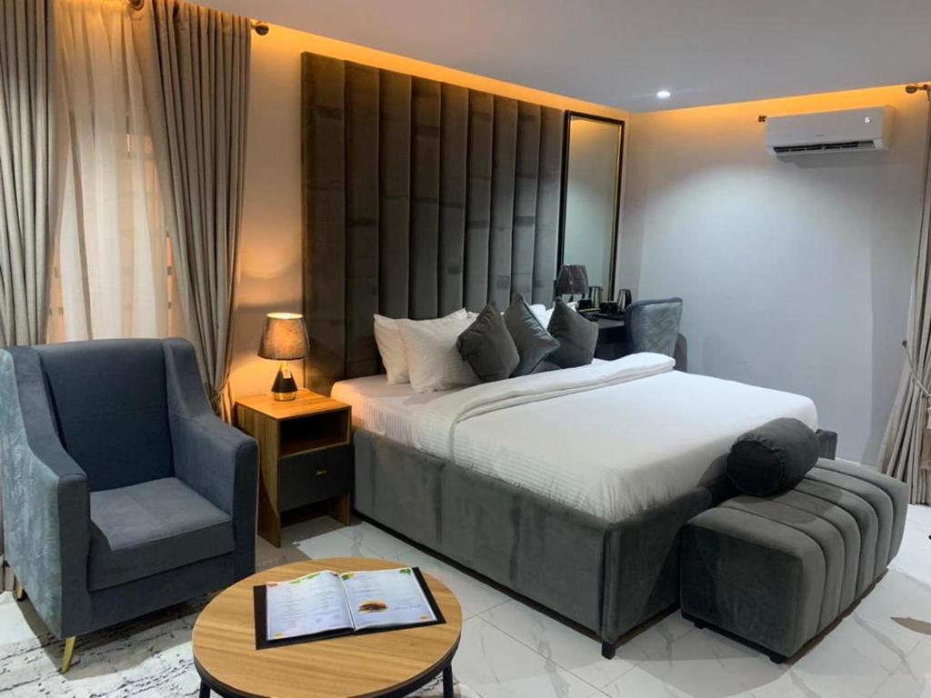 ein Schlafzimmer mit einem Bett, einem Stuhl und einem Tisch in der Unterkunft Choice Suites Signature in Ikeja