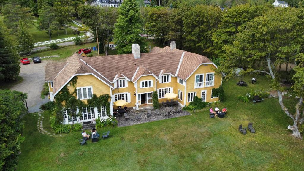 una gran casa amarilla con gente sentada en el césped en Auberge sur la Côte en La Malbaie