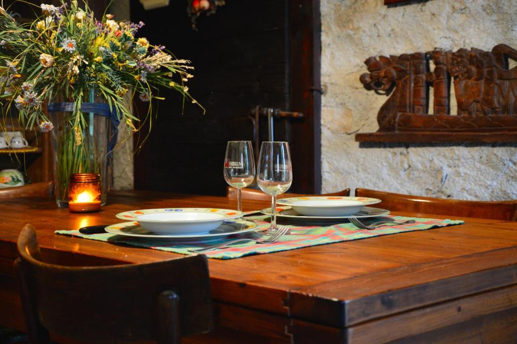 una mesa de madera con copas de vino y platos en ella en Baita Borgo Incantato, en Morbegno