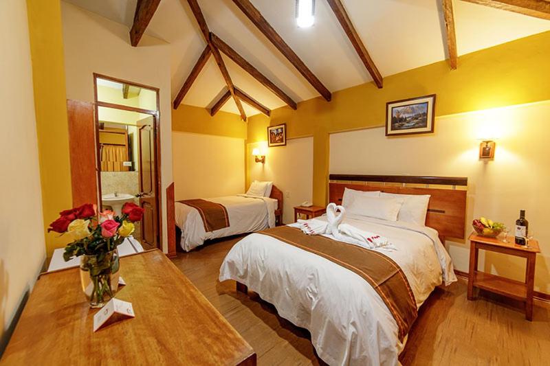 una habitación de hotel con 2 camas y un jarrón de flores en LILIUM VALLEY, en Ollantaytambo
