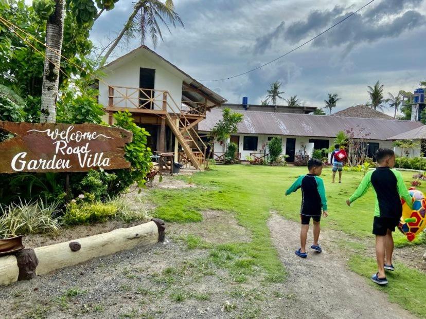 two boys walking towards a resort sign in front of a building at Road Garden Villa in General Luna