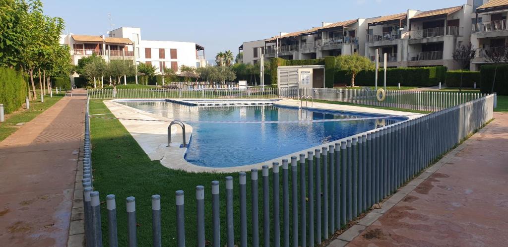 a fence around a swimming pool in front of a building at Precioso apartamento con dos terrazas privadas in Sant Jordi