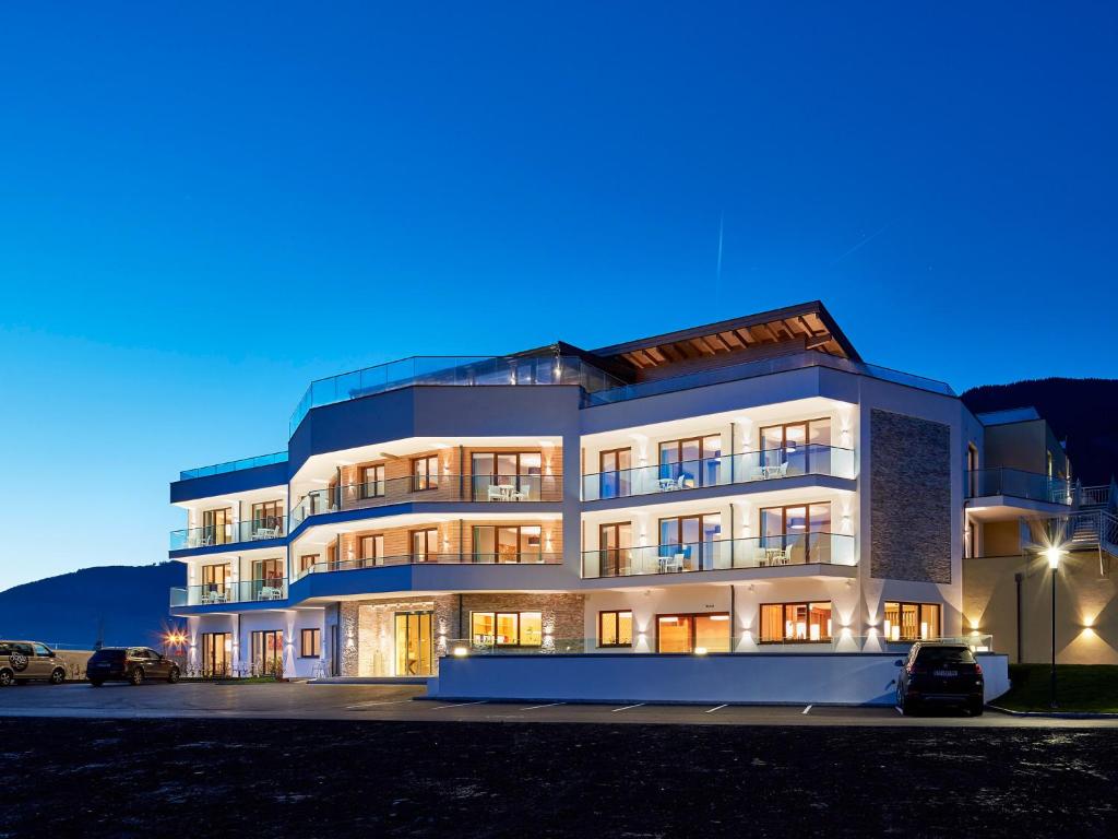duży biały budynek z oknami w nocy w obiekcie Sonja Alpine Resort w mieście Piesendorf