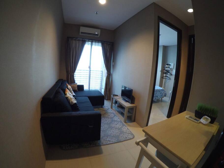 a living room with a black couch and a mirror at Strategic Cozy Hang Out Apartment, GP Plaza in Jakarta