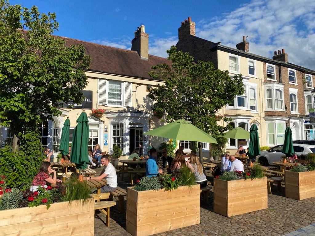 un grupo de personas sentadas en mesas frente a un edificio en The George Hotel Easingwold, en Easingwold