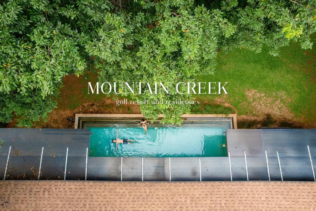 una piscina con un cartel que lee el arroyo de montaña en Mountain Creek Golf Resort & Residences, en Si Khio