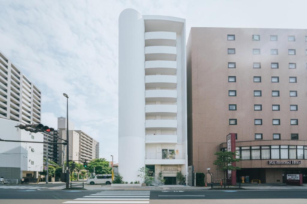 a tall white building on a city street at Of Hotel in Sendai