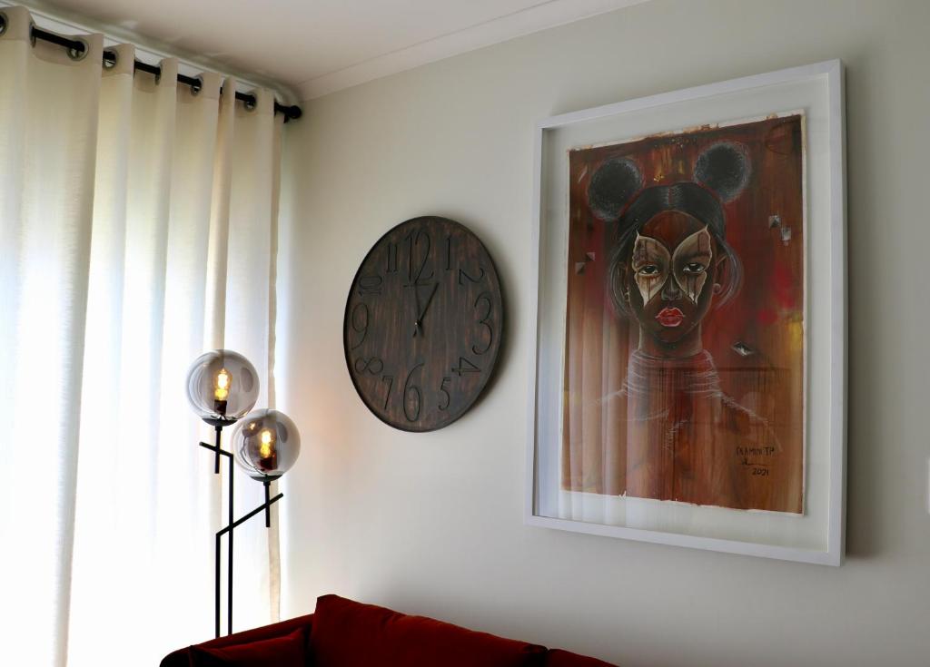 een klok hangend aan een muur naast een schilderij bij The Red Portrait at Carlswald in Midrand
