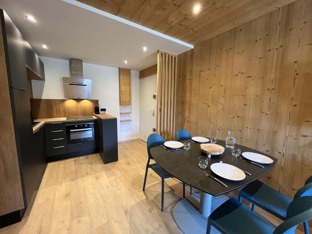 une salle à manger avec une table et des chaises et une cuisine dans l'établissement Appartement rénové 3* avec balcon et Wifi, proche pistes, idéal famille - FR-1-598-110, aux Gets