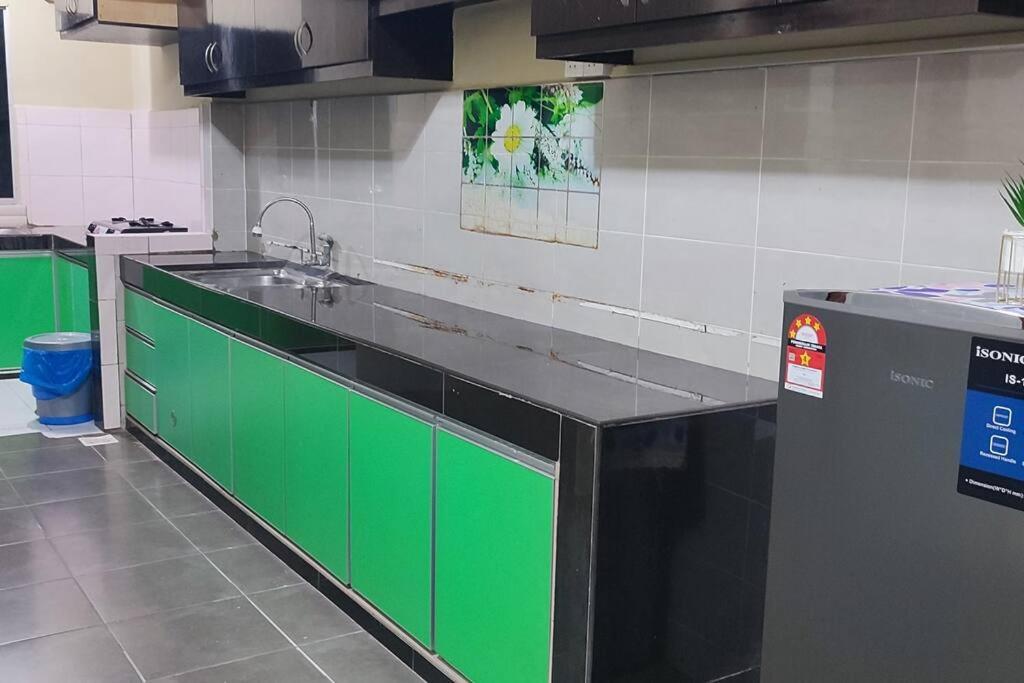 een keuken met groene kasten en een wastafel bij *IA D'CHATIN HOMESTAY MENTAKAB* in Mentekab