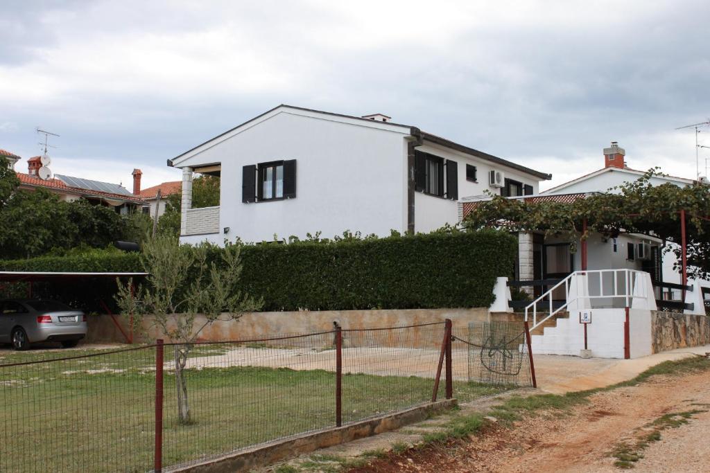 a white house with a fence in front of it at Apartments with a parking space Zambratija, Umag - 7059 in Zambratija
