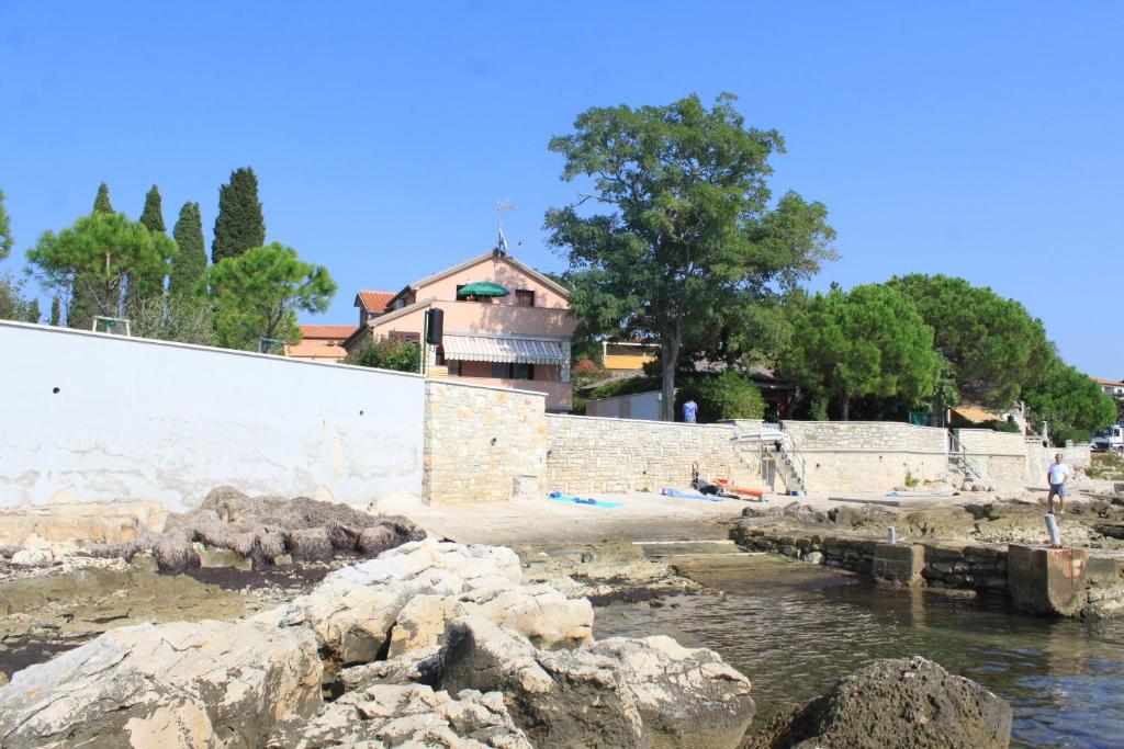 a body of water with rocks in front of a building at Apartments by the sea Zambratija, Umag - 6997 in Zambratija