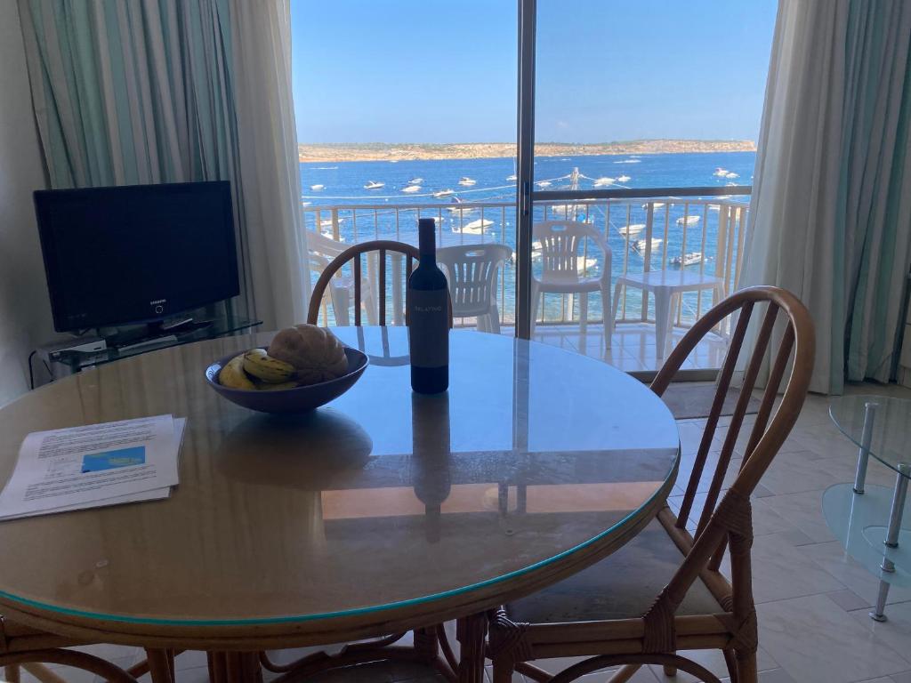 einen Tisch mit einer Flasche Wein und einer Schale Obst in der Unterkunft Sea front apartment at Mellieha Bay, Malta! in Mellieħa
