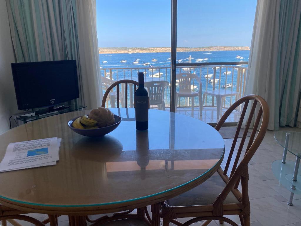 a table with a bottle of wine and a bowl of fruit at Sea front apartment at Mellieha Bay, Malta! in Mellieħa