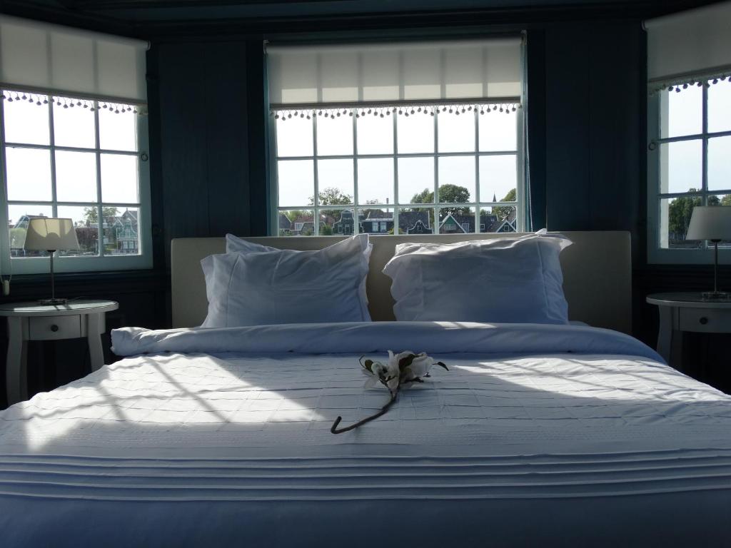 a blue bedroom with a large white bed with windows at Heerlijck Slaapen op de Zaanse Schans in Zaandam