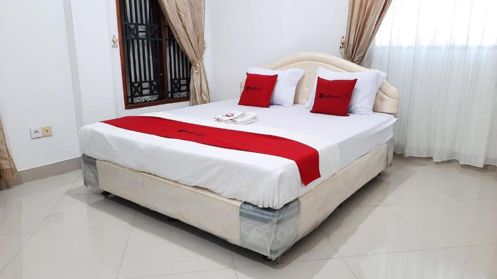 Tobadi的住宿－RedDoorz @ Gerson Hotel Abepura，一间卧室配有一张带红色枕头的大床