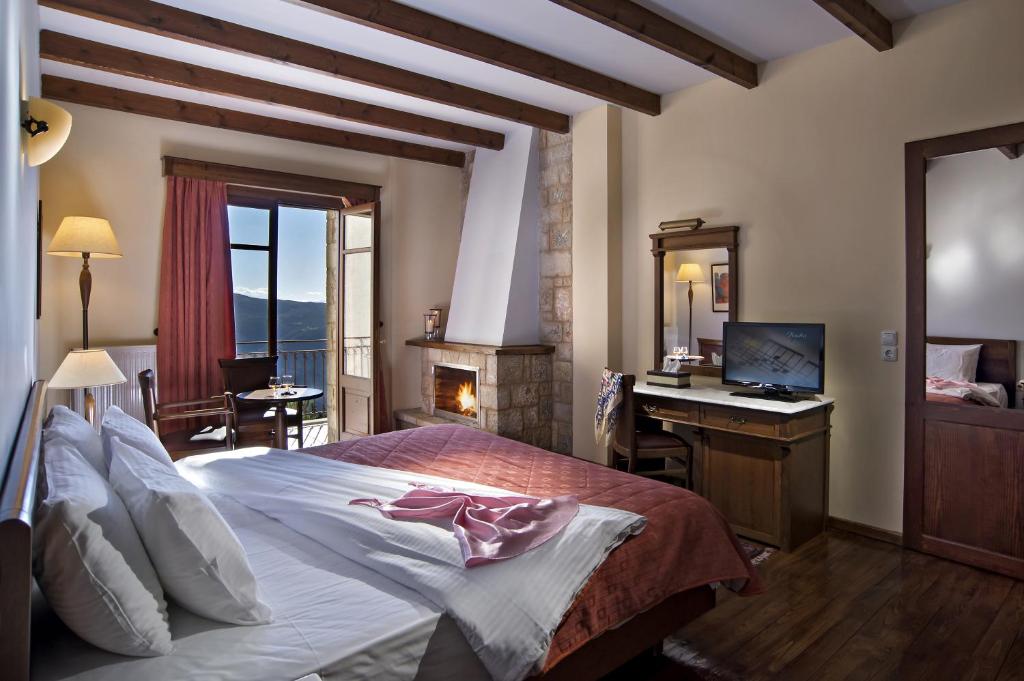 a bedroom with a bed and a desk with a computer at Alpen House Hotel & Suites in Arachova