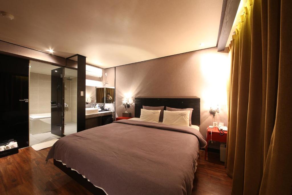 a bedroom with a large bed and a bathroom at Hotel Frenchcode in Busan