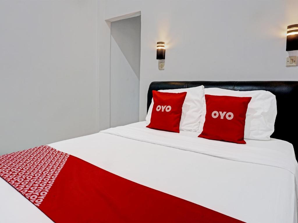 a red and white bed with two red pillows at OYO 91599 Penginapan Mutiara Madiun in Madiun