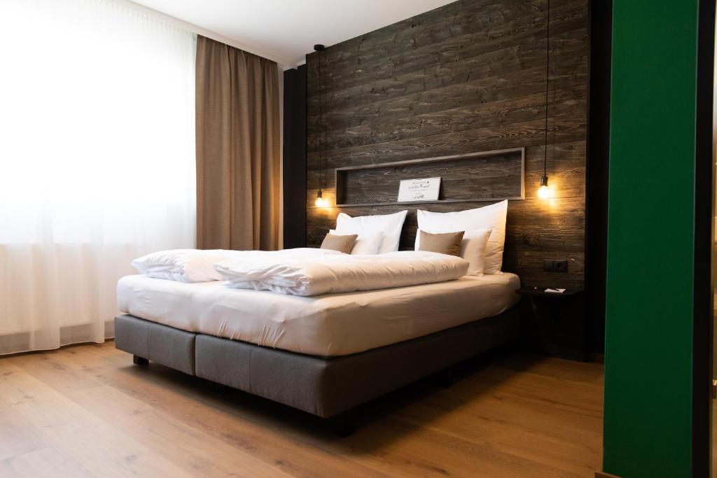 a bedroom with a large bed with a wooden wall at Self-Check-in Hotel VinoQ Zistersdorf in Zistersdorf
