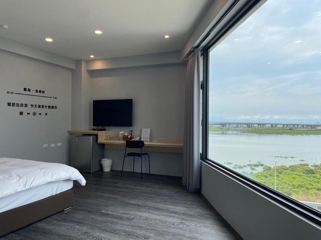 a bedroom with a large window with a view of a river at H Suite Sea in Lugang