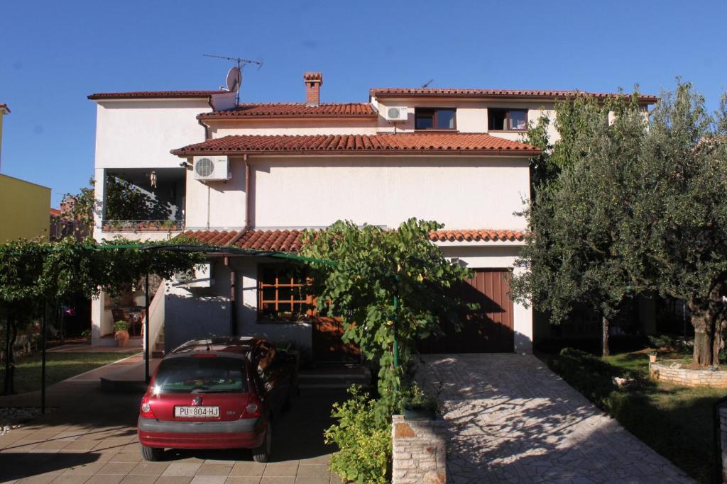 a red car parked in front of a house at Apartments with parking space Fazana - 7153 in Fažana