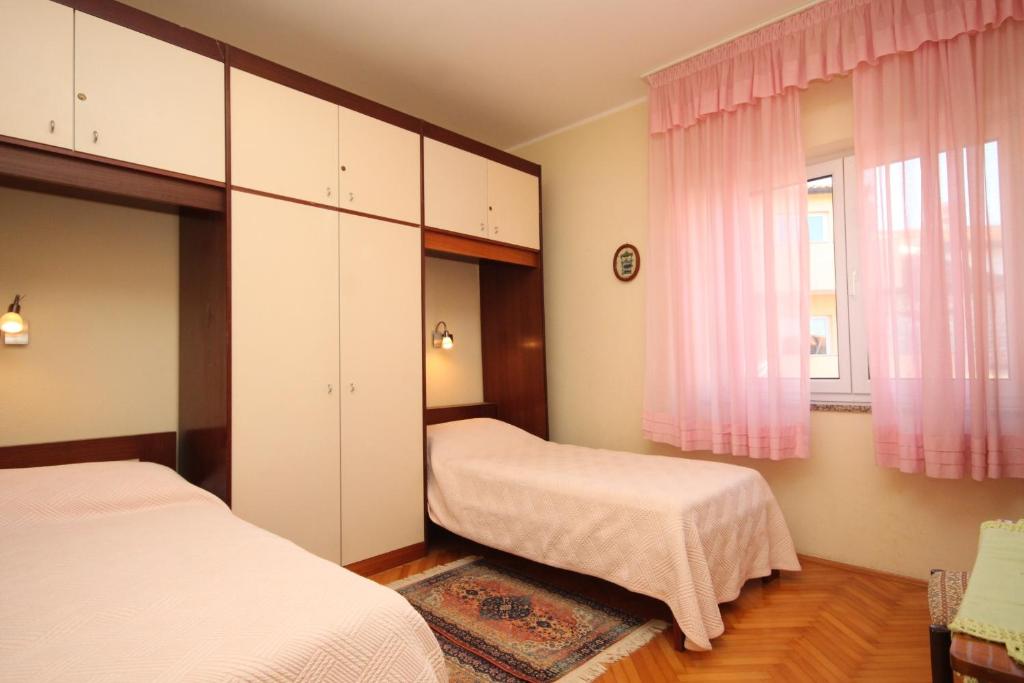 sypialnia z 2 łóżkami i oknem z różowymi zasłonami w obiekcie Apartments with a parking space Umag - 7147 w mieście Umag