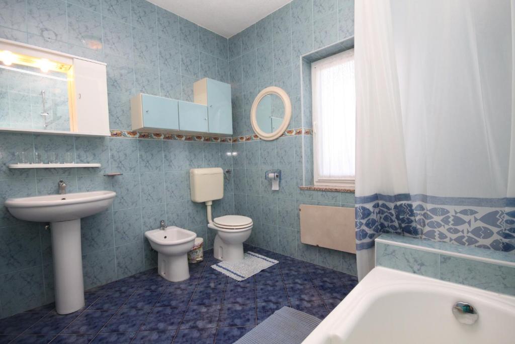 łazienka z 2 toaletami, umywalką i wanną w obiekcie Apartments with a parking space Umag - 7147 w mieście Umag