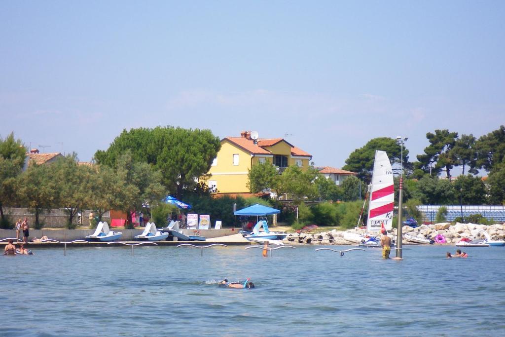 eine Gruppe von Menschen auf dem Wasser mit einem Segelboot in der Unterkunft Family friendly seaside apartments Novigrad - 7118 in Novigrad Istria