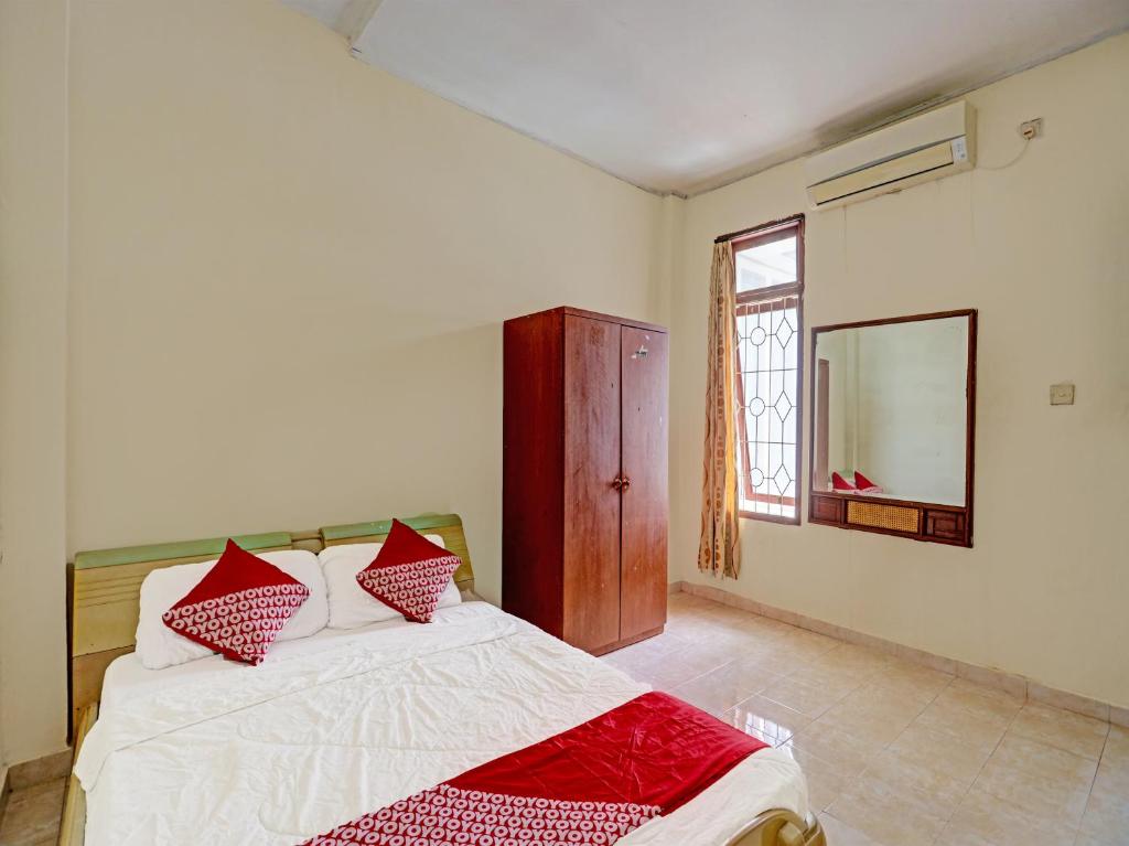 - une chambre avec un lit doté d'oreillers rouges et d'un miroir dans l'établissement OYO 91636 Kak Dadut Homestay, à Batam Center