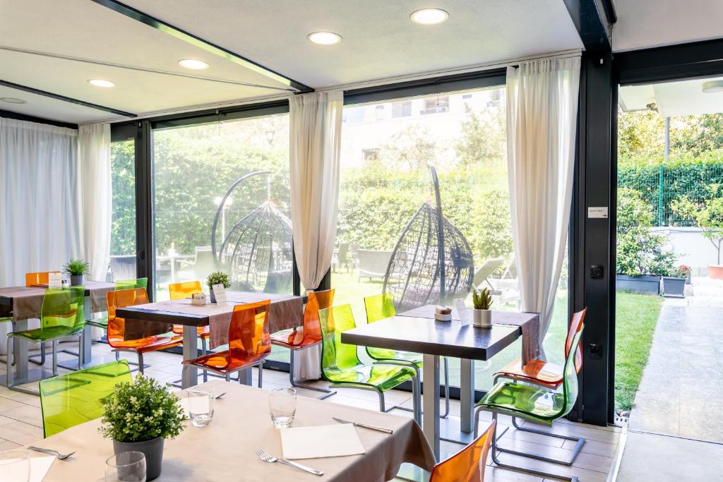 a restaurant with tables and chairs and large windows at Acca Palace - AA Hotels in Milan
