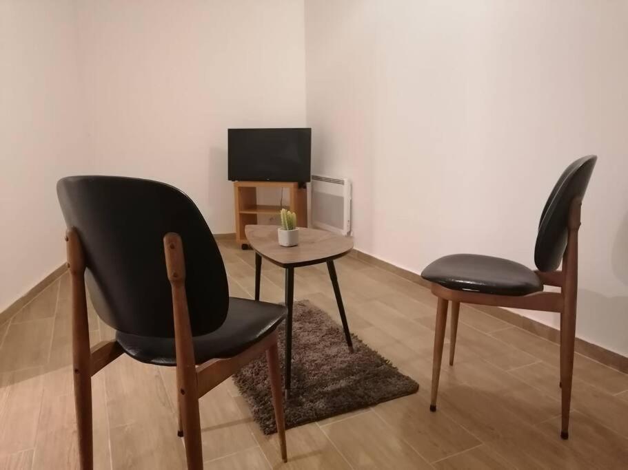 due sedie e un tavolo con televisore in una stanza di Superbe logement(B) avec Parking Gratuit sur place a Drancy