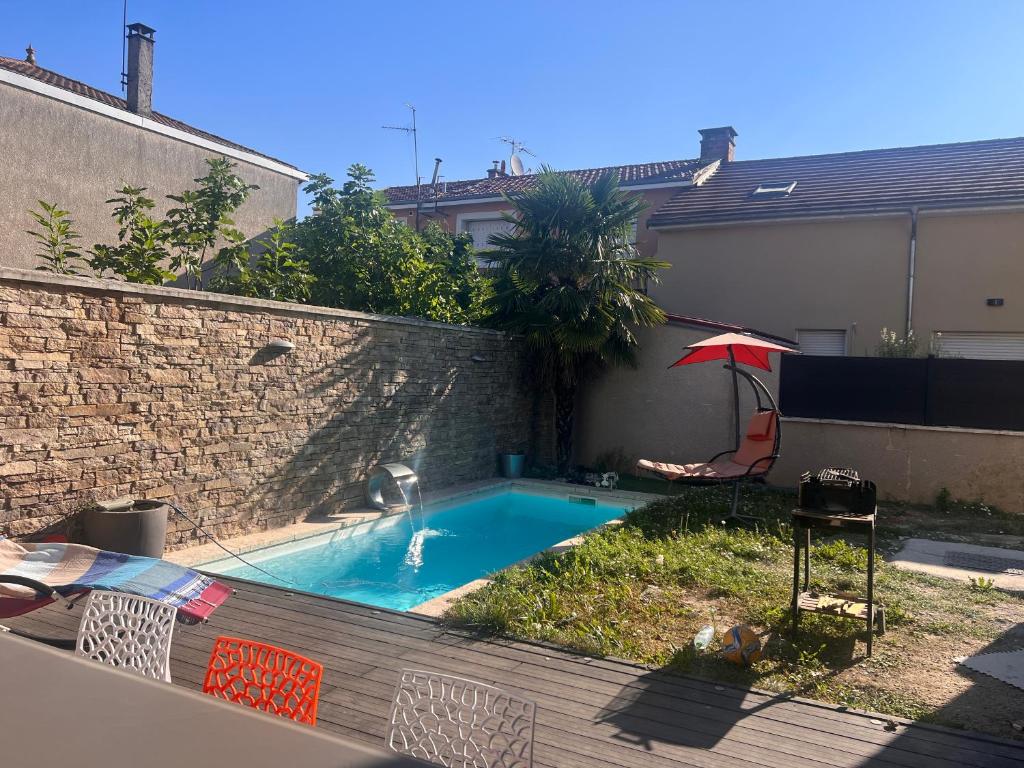 a small swimming pool in a backyard with a brick wall at Maison moderne et spacieuse avec piscine in Villeurbanne