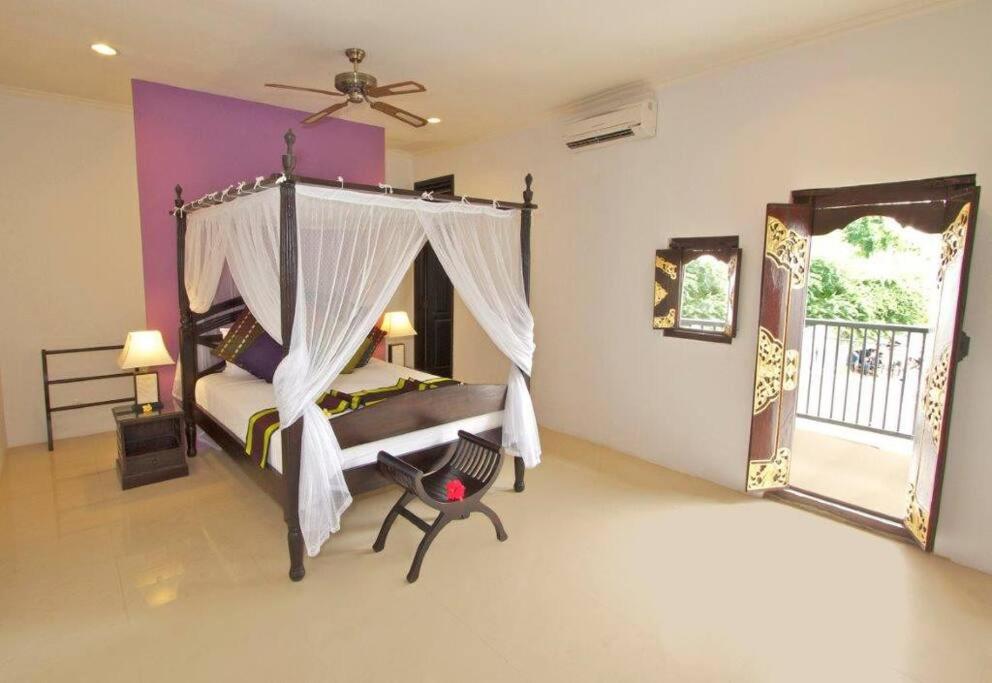 a bedroom with a canopy bed and a balcony at 5 Bedroom Holiday Villa - Kuta Regency B8 in Kuta