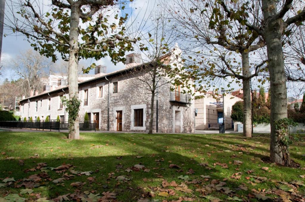 una antigua casa de piedra con árboles en el patio en Apartamentos María Luisa, en Burgos