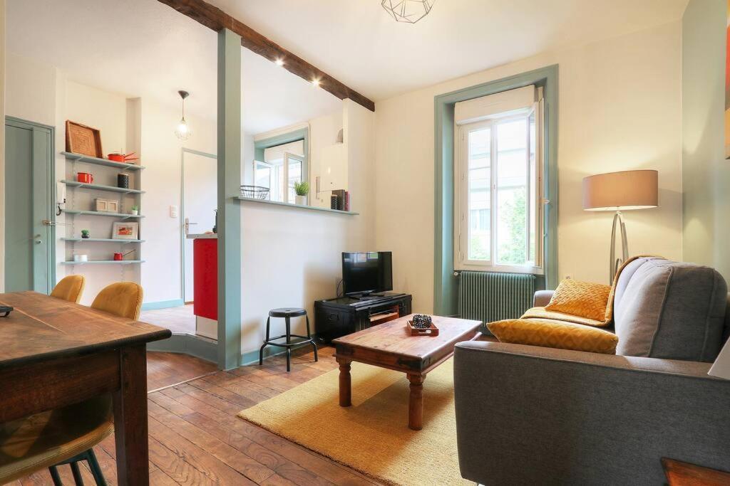 uma sala de estar com um sofá e uma mesa em Le Beaumont em Rennes