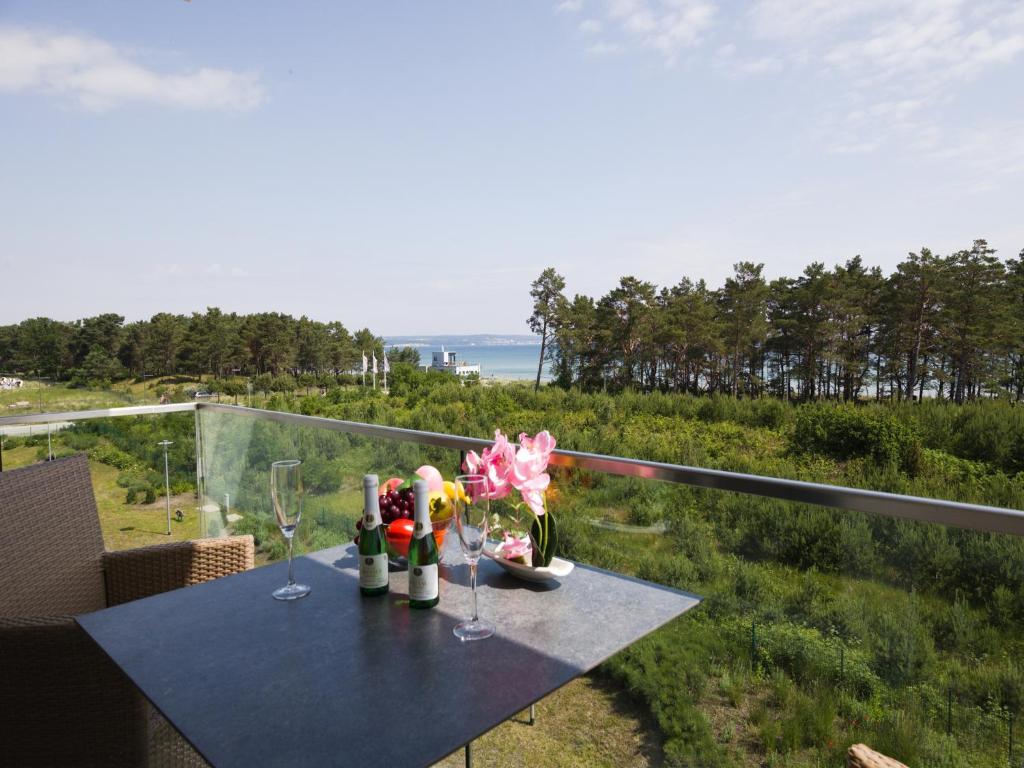 - une table avec des verres à vin et des fleurs sur le balcon dans l'établissement Dünenresidenz Prora - Ferienwohnung mit Meerblick, 1 Schlafzimmer und Balkon NP-310, à Binz