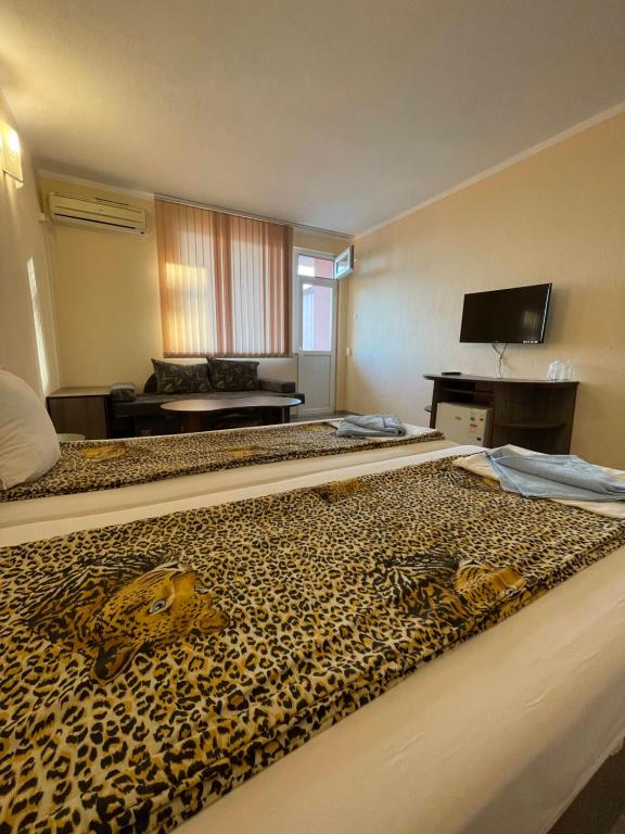 a hotel room with two beds with a leopard print blanket at Къща за гости Kita in Sveti Vlas