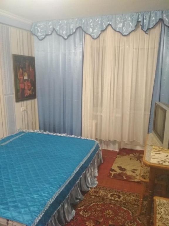 a bedroom with a blue bed in a room with curtains at Уютная 1 комнатная квартира возле метро Дарница in Kyiv