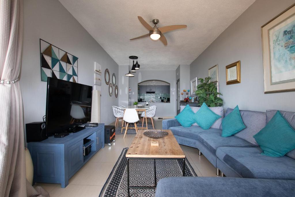 a living room with a blue couch and a tv at The Bay 4 in Ballito